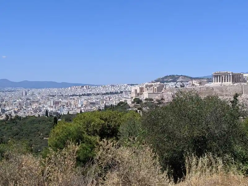 Panoramic landscape with Acropolis and Parthenon framed by greenery and urban Athens